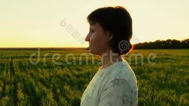落日背景下年轻女子站在绿色草坪上的肖像